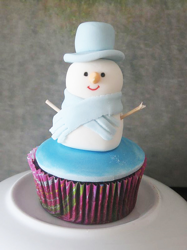 Снеговик из мастики в голубой шапке и шарфе на капкейке
